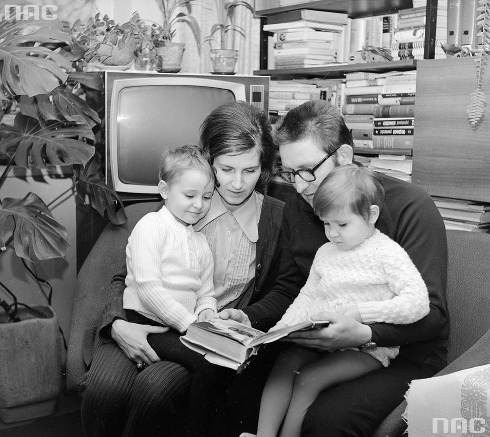 Rodzice czytają książkę z dziećmi. W tle widoczny telewizor Granit 101 i regał z książkami, 1973, fot. Grażyna Rutkowska / NAC