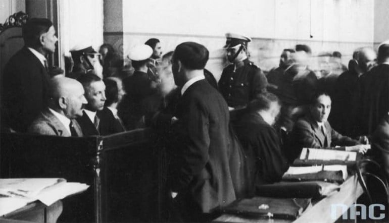 Proces Taty. Widok na ławę oskarżonych w czasie rozprawy. Widoczni m.in.: Łukasz Siemiątkowski (siedzi z lewej łysy), Pantaleo Karpiński (siedzi obok Ł. Siemiątkowskiego), 1932, fot. Koncern Ilustrowany Kurier Codzienny - Archiwum Ilustracji / Narodowe Archiwum Cyfrowe (NAC)