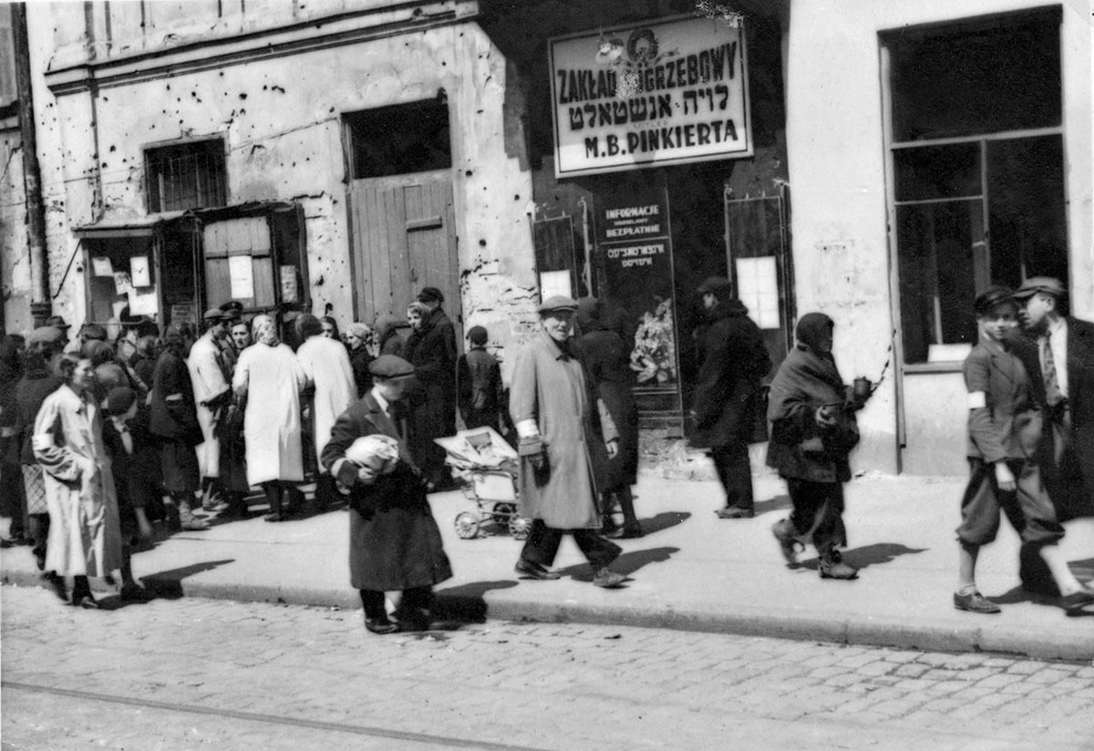 Przechodnie na ulicy Warszawskiego getta obok zakładu pogrzebowego "Wieczność" Mordechaja Pinkerta, 1940-1942. Foto: ZIH/ Forum