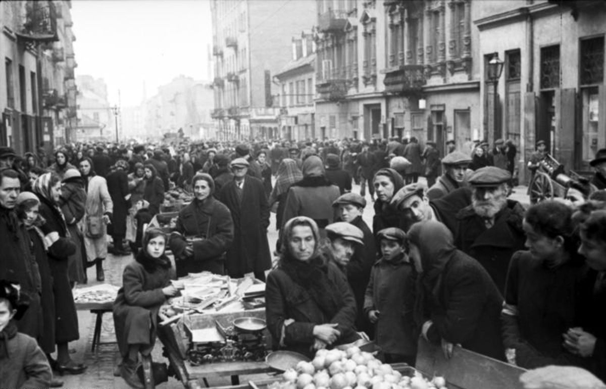 Tłum ludzi handlujących i kupujących na ulicy w getcie warszawskim.  Kamienice w tle.