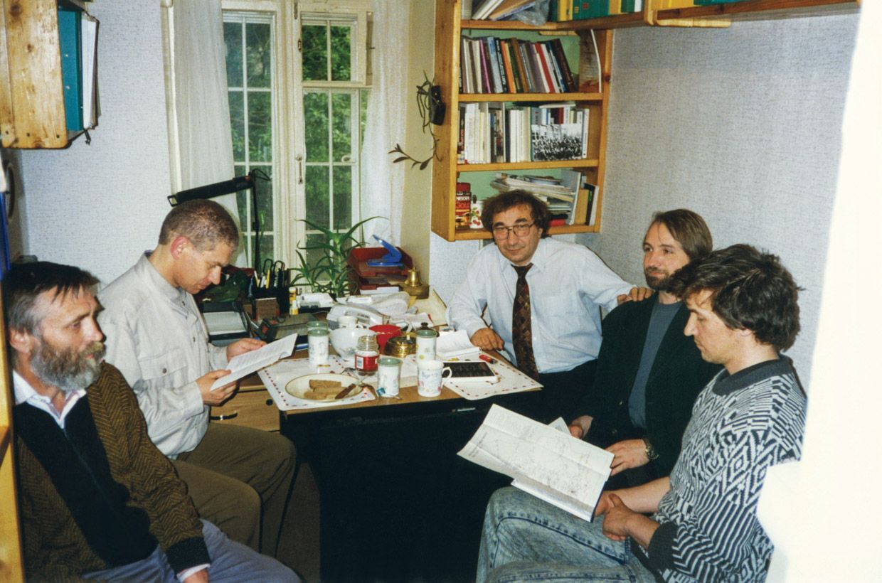 Группа мужчин за столом в небольшой комнате 